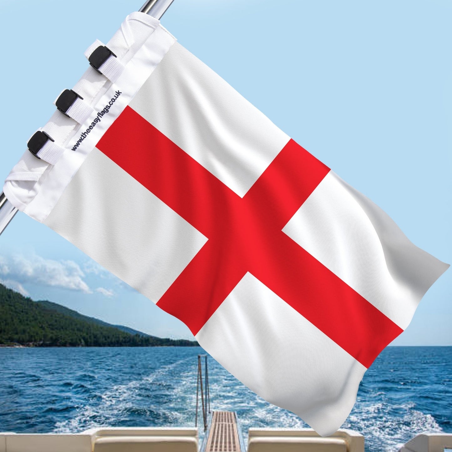 England national flag with bold red cross on white background, mounted on a boat rail with a universal triple-lock system, flying at sea with blue sky and coastline in the background